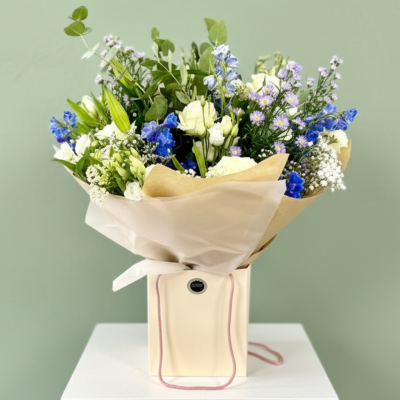 Bluebell Breeze - Fresh blue and white blooms with eucalyptus presented in a stylish flower bag arrangement.