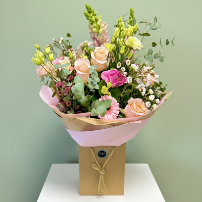Blush Meadow - Soft peach roses, seasonal blooms and textured foliage arranged in a lilac hatbox for a delicate pastel look.