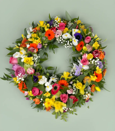 Vibrant Wreath - A colourful and uplifting wreath designed to celebrate a life filled with warmth, happiness, and cherished moments. Arranged in a vibrant palette with a variety of delicate textures and fresh greenery, this circular tribute symbolises eternity, remembrance, and the lasting impact of a loved one’s life. Its joyful appearance offers a heartfelt way to honour treasured memories while bringing comfort and reflection to family and friends during a funeral service, memorial, or celebration of life.