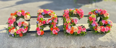 Letters - A beautifully crafted letter tribute designed to create a deeply personal farewell for a cherished loved one. Arranged in soft, uplifting tones with vibrant accents and fresh greenery, this bespoke design offers a heartfelt expression of love, remembrance, and gratitude. Each letter is carefully created to form a meaningful word or name, making it a fitting centrepiece for funeral services, memorial ceremonies, or celebrations of life. A touching tribute that honours a unique life and preserves treasured memories for family and friends.