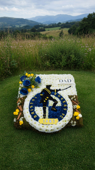 Personalised Football Badge Tribute - Celebrate a loved one’s passion for football with a personalised football badge floral tribute, lovingly handcrafted by Seasons Florist.

Featuring a detailed football club crest created using carefully arranged fresh flowers, this bespoke design can be made to represent any football team or club badge, using their colours and emblem to create a truly personal farewell.

Whether they were a lifelong supporter of their favourite team or simply loved the beautiful game, this tribute offers a meaningful way to honour their passion and celebrate the memories they leave behind.

Each design is individually handcrafted with care and attention to detail, with the choice of club badge, team colours and personalised lettering tailored to your wishes.

Created by Seasons Florist, Portishead, our bespoke football tributes provide a thoughtful and personal way to say a final goodbye.

Any team. Any badge. A tribute as unique as the person you’re remembering.

All football badge tributes are made to order. Please contact us to discuss your chosen club, colours, lettering and design. Final designs are subject to feasibility and flower availability.